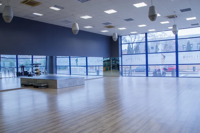 Sala de actividades dirigidas con suelo de madera y grandes ventanales